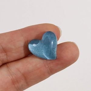 Macro shot of 15-20mm sky blue resin heart charm with internal shimmer and glitter texture