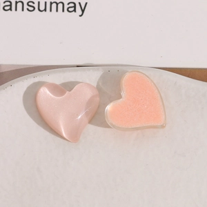Macro detail of heart-shaped resin charms in pearl pink and glitter orange for DIY crafts