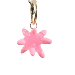 Chic golden hoop earring with vibrant pink textured starburst pendant on white background