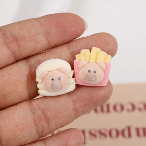 Macro shot of flocked cartoon pig charms in burger and fries shapes for DIY crafts