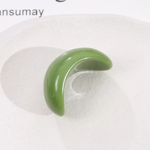 Vue macro d'un composant de bijou en résine vert herbe lisse en forme de croissant