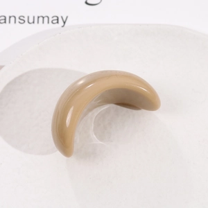 Détail d'une pince à cheveux en résine en forme de croissant kaki sur plat blanc
