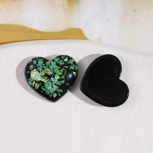 Macro shot of heart-shaped resin charms with black finish and gold foil flake inlay