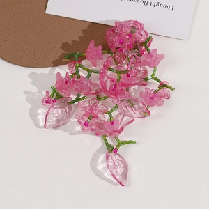 Detail of handmade beaded flower hair clip with translucent pink resin petals and green stems