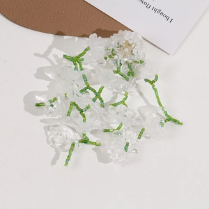 Close-up of handmade floral charm with transparent petals and green seed beads