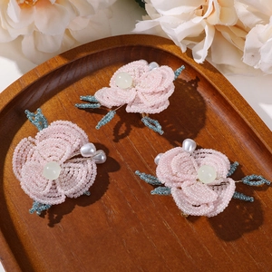 Tres flores de cuentas rosas hechas a mano con perlas y hojas sobre madera