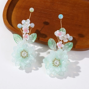 Détail d'un accessoire floral artisanal avec perles et pétales verts dégradés