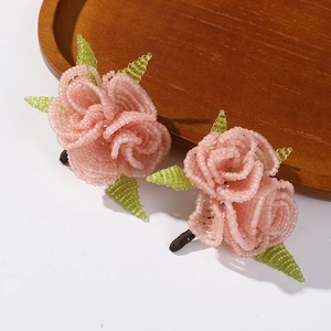 Exquisite handmade beaded pink rose earrings with green leaf details on wood base