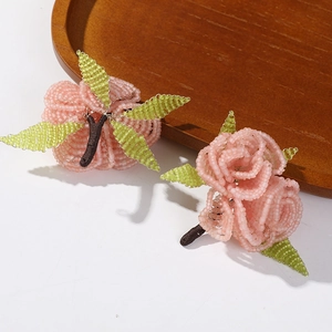 Macro detail of handmade beaded pink rose with green leaves for jewelry making