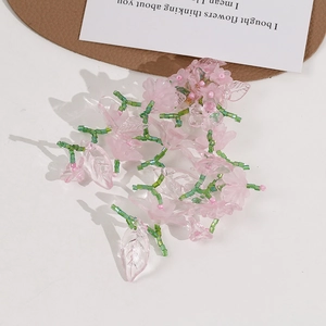 Detailed view of DIY pink translucent flower petals and green tube beads on white background