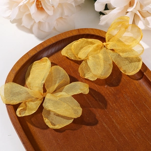 Nahaufnahme von goldenen Schmetterlings-Haaraccessoires aus Organza auf Holztablett