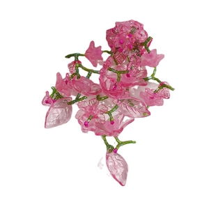 Handmade pink flower cluster beadwork accessory with green stem on white background