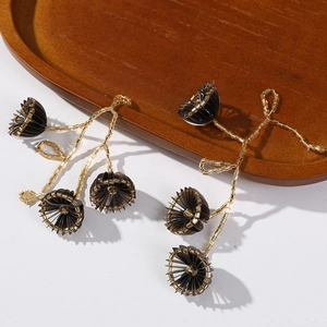 Detailaufnahme von handgemachten Blumenohrringen mit Goldperlen und braunen Falten