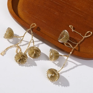 Handgefertigte goldene Perlenohrringe mit Blumenmuster auf einem Holztablett