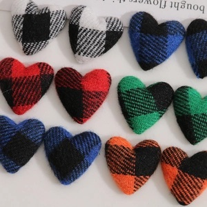 Macro shot of colorful plaid fabric heart buttons with detailed woven texture on white