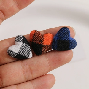 Close-up of heart-shaped plaid fabric patches in black, orange, and blue for DIY projects