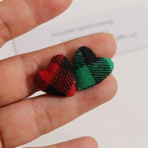Close-up of red and green plaid fabric heart buttons for DIY jewelry making and crafts