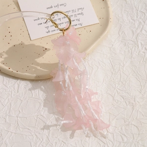 Pink acrylic flower bead tassel earrings with golden hoop on a cream ceramic plate