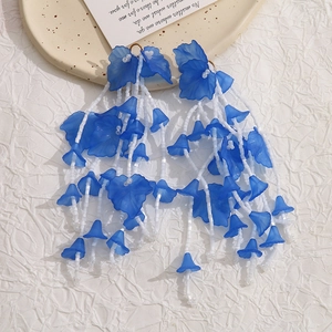 Bohemian royal blue flower petal earrings with long white beaded tassels on a beige plate