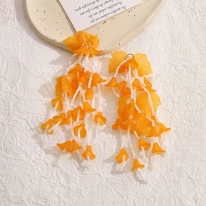 Orange acrylic flower long tassel drop earrings with white glass beads on textured cloth