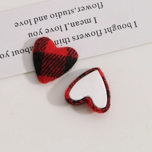 Macro detail of plaid heart buttons with red and black buffalo check fabric and silver metal back