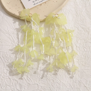 Detailed close-up of long tassel flower earrings with light yellow acrylic petals