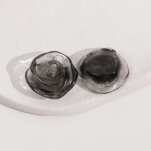 Gros plan macro de boucles d'oreilles roses en résine noire fumée avec texture marbrée