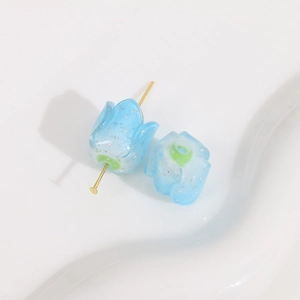 Close-up of light blue resin tulip flower bead with gold glitter for DIY jewelry making