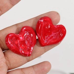 DIY red resin heart pendants with marble texture shown held in hand for scale
