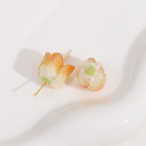 Macro detail of tulip-shaped acrylic beads with golden glitter for DIY jewelry making