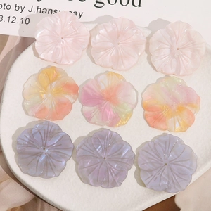 Detalle macro de dijes florales perlados DIY en tonos degradados rosa, naranja y lila