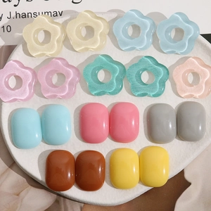 Colorful floral and oval resin charms for DIY jewelry making displayed on a white tray