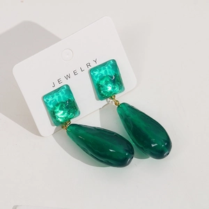 Detail of dark green resin earrings with water ripple texture and golden studs