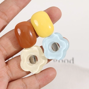 Close-up of four glitter resin hair clips in capsule and flower shapes with metal bases