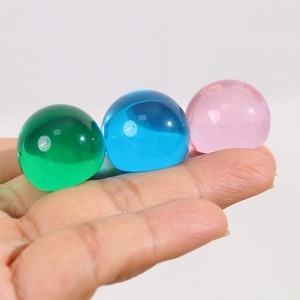 Détail macro de trois perles demi-rondes en résine translucide de 22mm en vert, bleu et rose