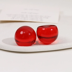 Détail macro de perles en résine rouge translucide sur plateau blanc pour DIY