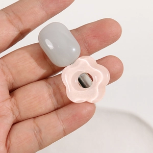 Detail of candy-colored resin jewelry charm with pink petal and gray oval bead