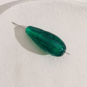 Close-up of translucent dark green teardrop bead with irregular textured surface