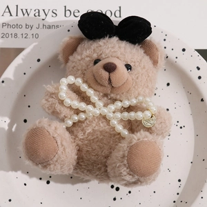 Brown plush bear accessory with black velvet bow and faux pearl chain decoration