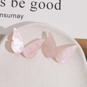 Detail van roze acetaat vlinderbedeltje met parelmoer textuur voor DIY-sieraden