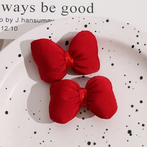 Close-up of vibrant red satin bow hair accessories on a decorative ceramic tray