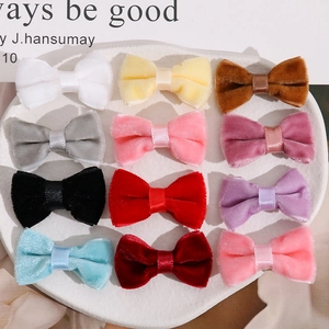 Detailed view of twelve colorful velvet bow hair clips arranged on a ceramic tray