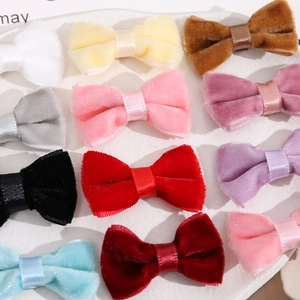 Detailed view of colorful velvet bow clips with satin ribbon centers on white surface