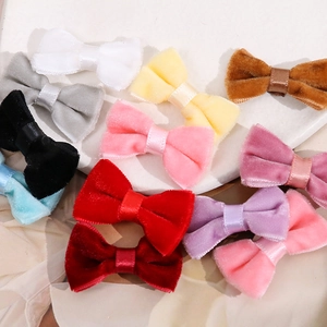 Handmade velvet bow hair accessories in multiple colors on a white ceramic tray