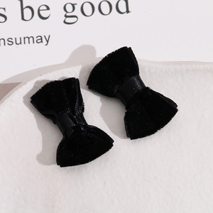 Close-up of elegant black velvet hair bows with ribbon centers on a white ceramic plate