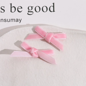 Detailed view of two pink velvet handmade bows on a textured white display plate