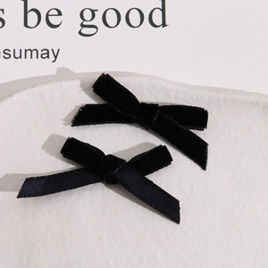 Elegant pair of black velvet ribbon bow hair clips on a minimalist white ceramic plate