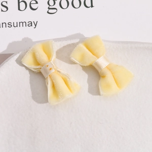 Close-up of a pair of soft cream velvet bow craft accessories on a white plate