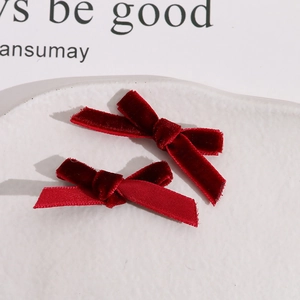 Close-up of two handmade dark red velvet bow hair clips on a ceramic tray display