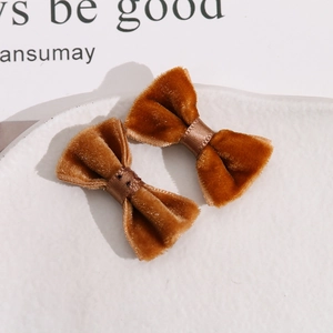 Detail of caramel brown velvet handmade bow tie accessories on a textured white tray